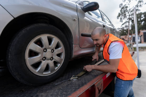 Latin American tow truck operator towing a car - roadside assistance concepts